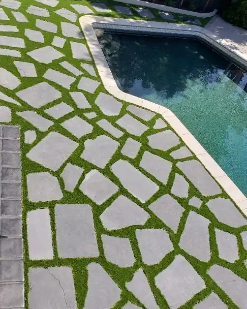 Flagstone set in artificial grass around a pool with new precast concrete coping